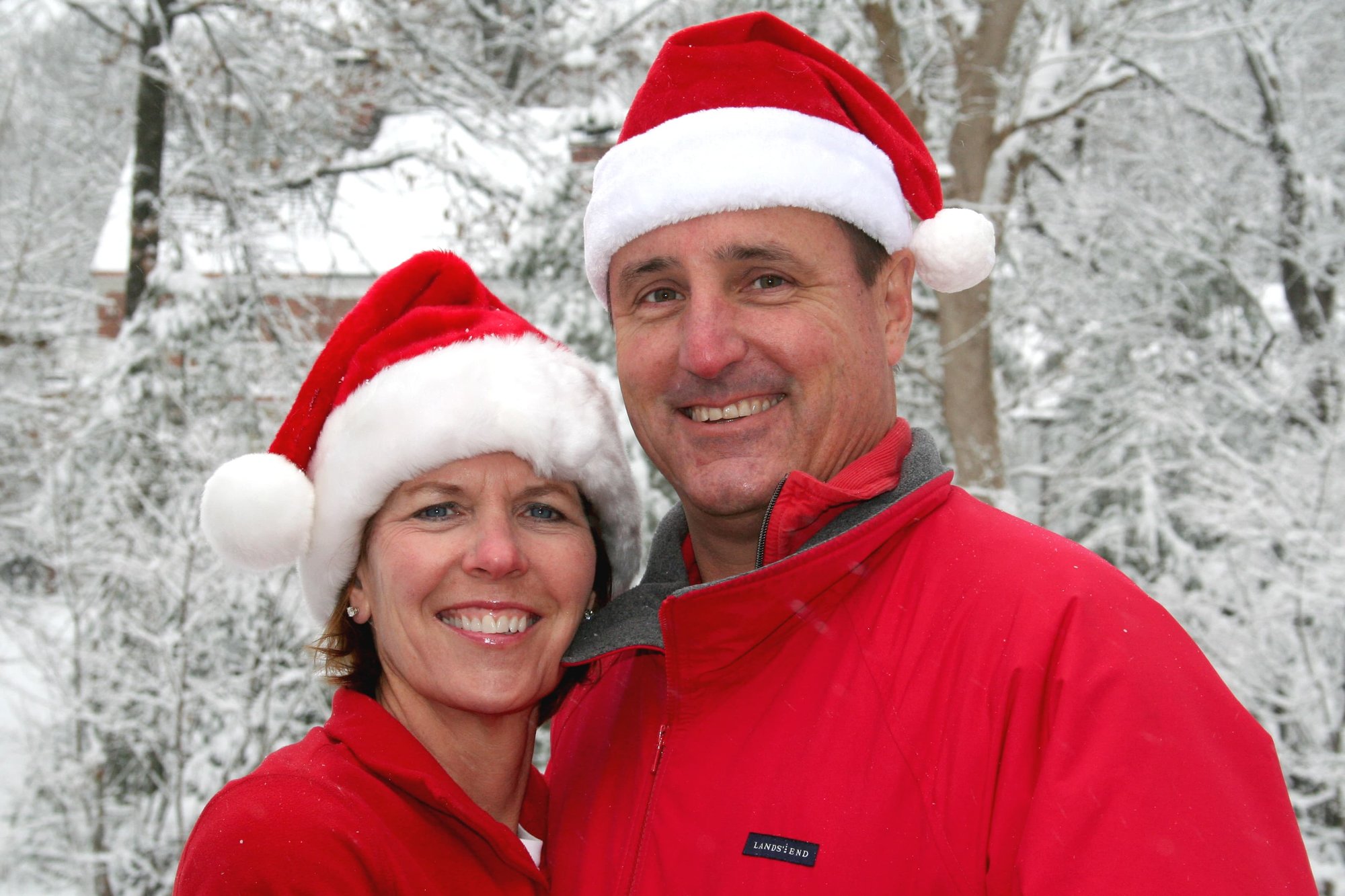Realtor Kate Wall and Her Husband, Dr Mike Wall, with red Santa hats on in front of a very shite snowy background.